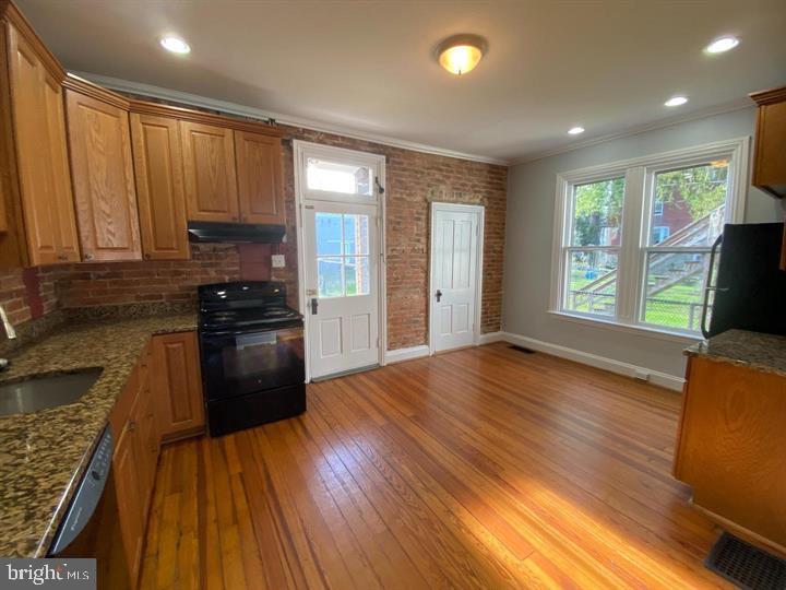 a kitchen with granite countertop wooden floors a stove and a refrigerator