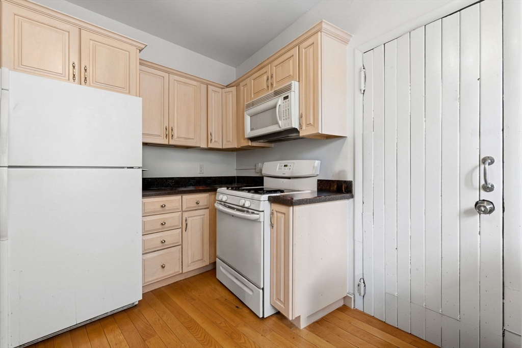 73 Parkman Street, Unit 1 Brookline, MA 02446 - Photo 5 of 10 a kitchen with a refrigerator a stove and white cabinets