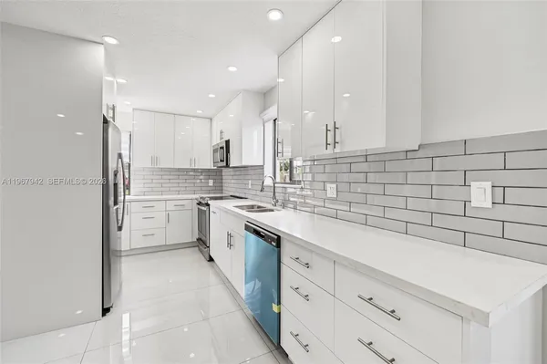 a kitchen with white cabinets appliances and a sink