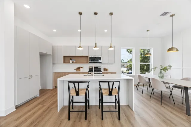 a kitchen with kitchen island a dining table chairs and white cabinets