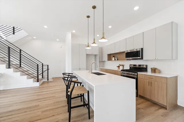a kitchen with stainless steel appliances kitchen island a wooden floor and white cabinets