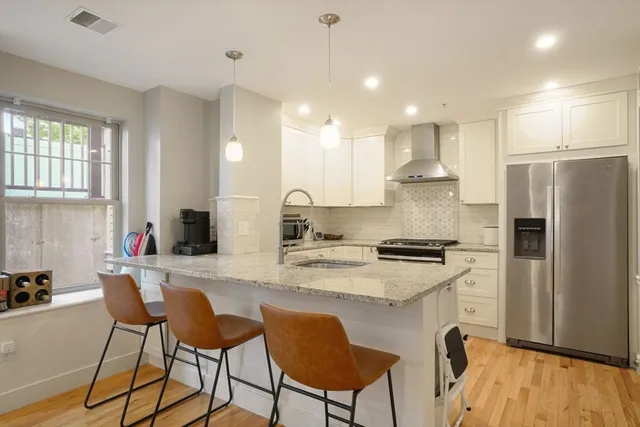 a kitchen with stainless steel appliances granite countertop a refrigerator a stove a sink dishwasher a dining table and chairs with wooden floor