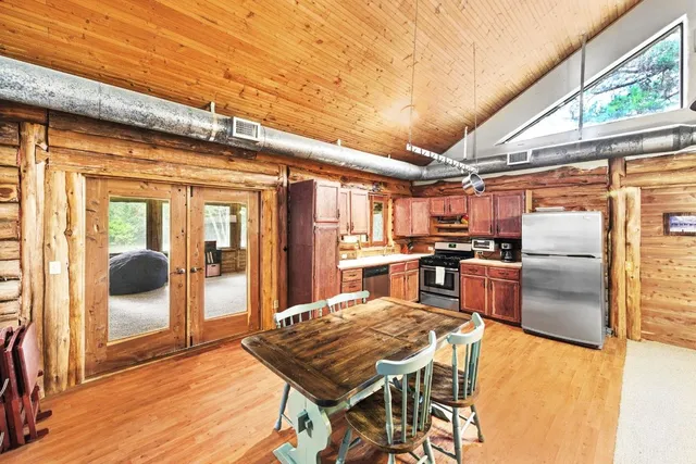 a kitchen with stainless steel appliances granite countertop a stove a refrigerator a oven with white cabinets and wooden floor