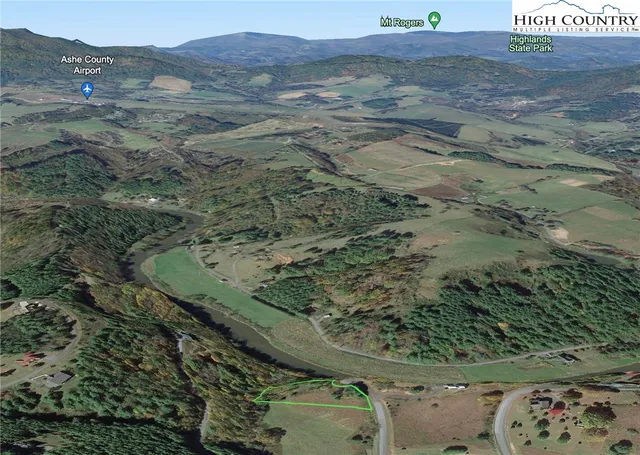 an aerial view of a house with outdoor space and trees all around