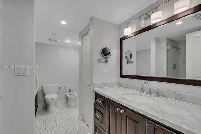 a bathroom with a granite countertop sink a toilet and a mirror