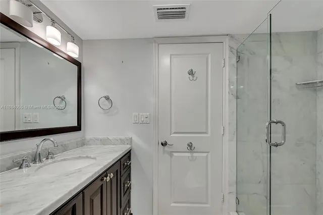 a bathroom with a granite countertop sink a mirror and shower
