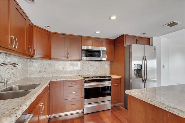 a kitchen with stainless steel appliances granite countertop a sink stove and refrigerator