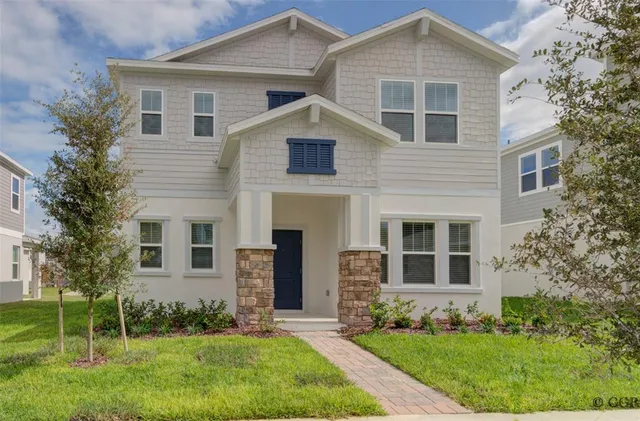 a view of a yard in front of a house with plants and large tree