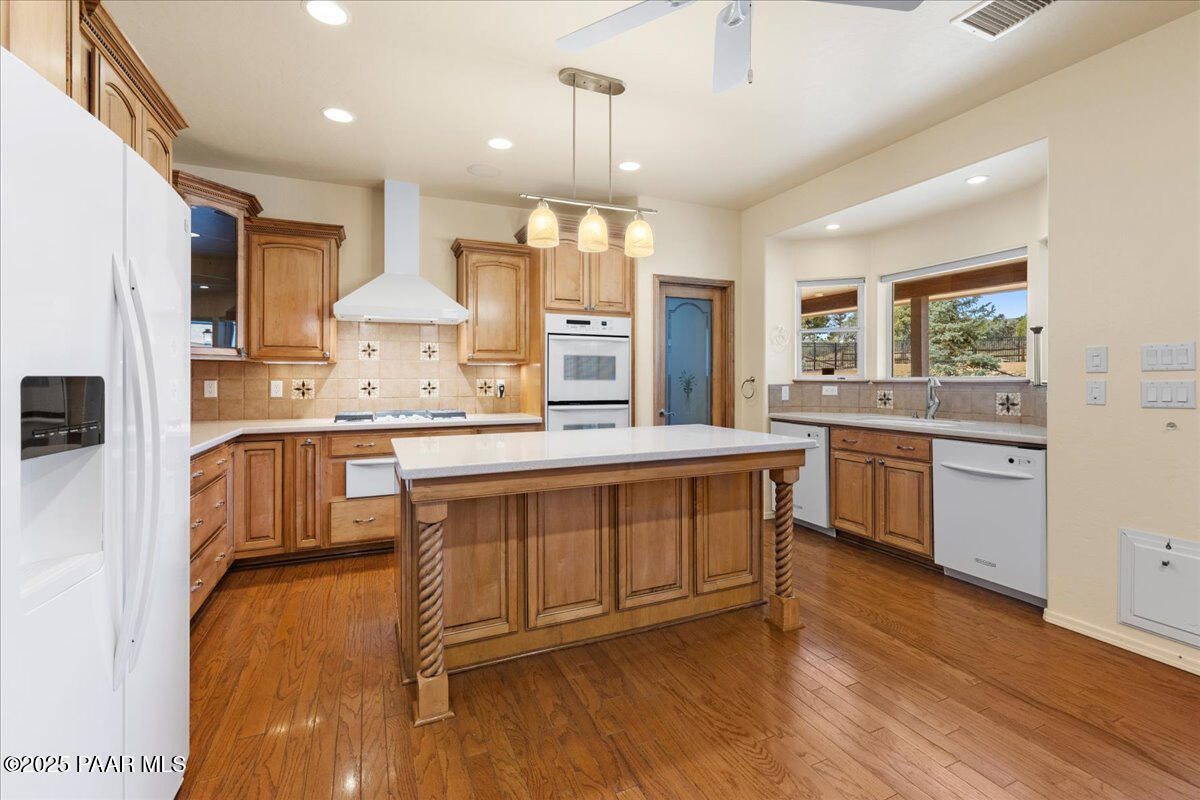 5540 Deer Spring Place Prescott, AZ 86305 - Photo 12 of 46 a kitchen with kitchen island granite countertop wooden floors and white cabinets