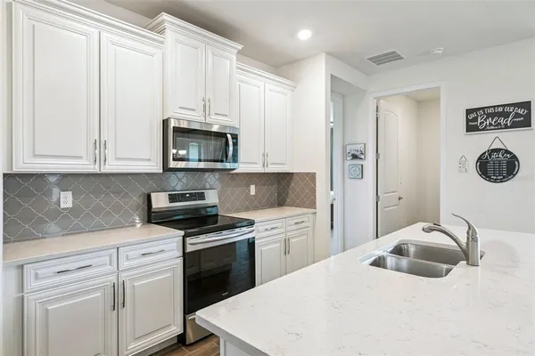 a kitchen with stainless steel appliances kitchen island granite countertop a sink a stove and cabinets