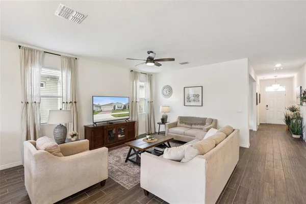 a view of a dining room and livingroom view with furniture wooden floor a chandelier