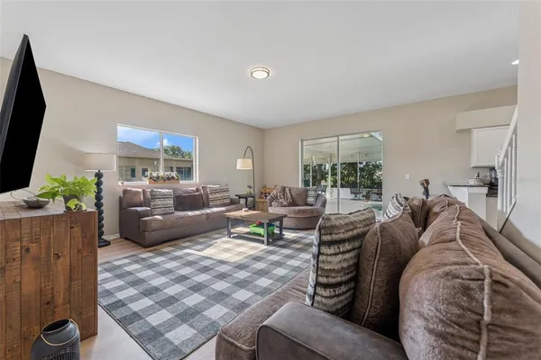 a living room with furniture a flat screen tv and a large window