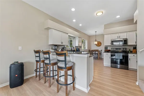 a kitchen with stainless steel appliances kitchen island granite countertop a stove a sink a refrigerator cabinets and dining table