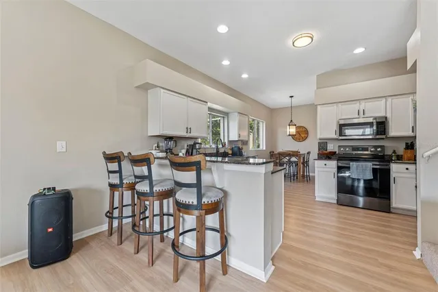 a kitchen with stainless steel appliances kitchen island granite countertop a stove a sink a refrigerator cabinets and dining table