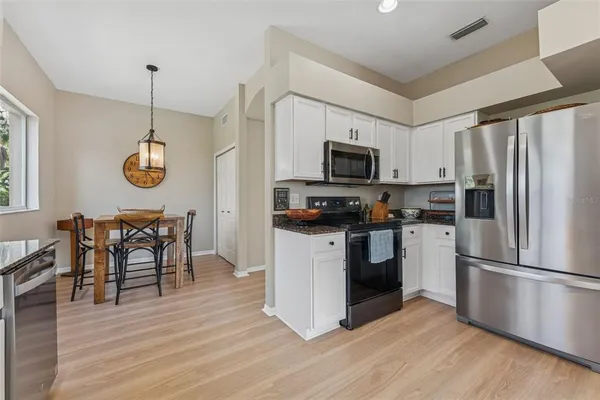 a kitchen with white cabinets stainless steel appliances and wooden floor