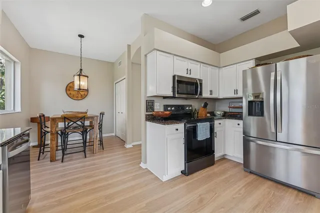 a kitchen with white cabinets stainless steel appliances and wooden floor