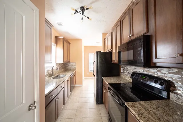 a kitchen with stainless steel appliances granite countertop a stove a sink dishwasher and a refrigerator