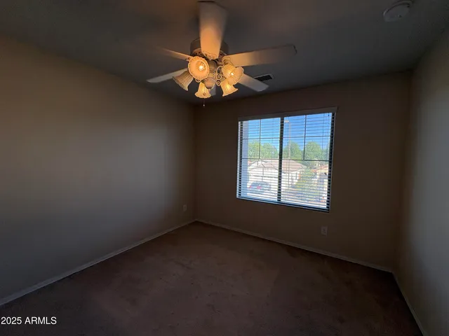an empty room with windows and chandelier fan