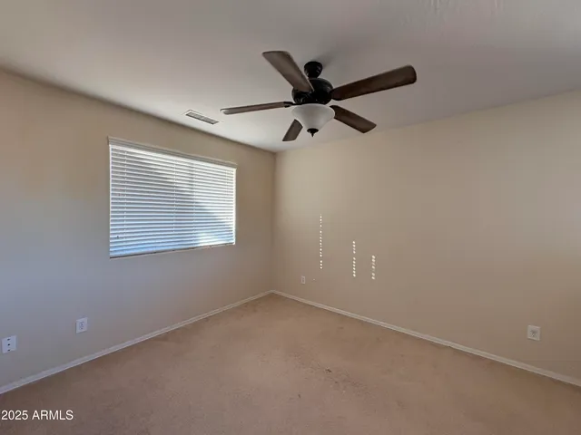 an empty room with a window and a fan