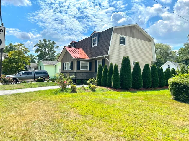 a front view of house with yard and trees in the background