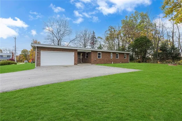 a front view of house with yard and trees in the background