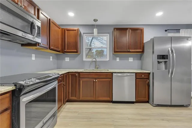 a kitchen with stainless steel appliances granite countertop a stove a sink and a refrigerator with wooden floor