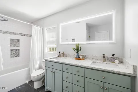a bathroom with a granite countertop sink toilet a large mirror a bathtub and shower