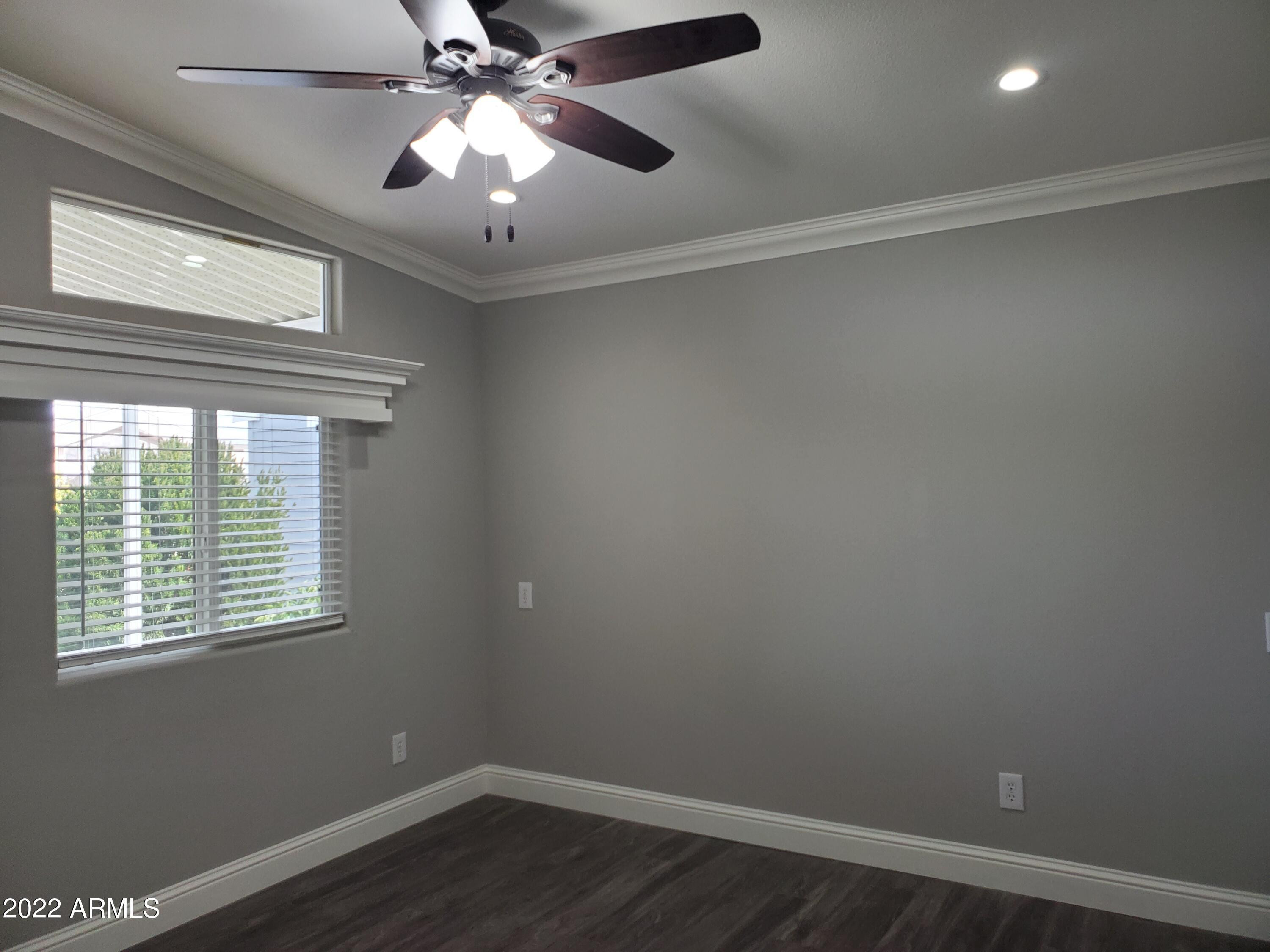 7750 East Broadway Road, Unit LOT 857 Mesa, AZ 85208 - Photo 15 of 17 an empty room with wooden floor chandelier fan and windows