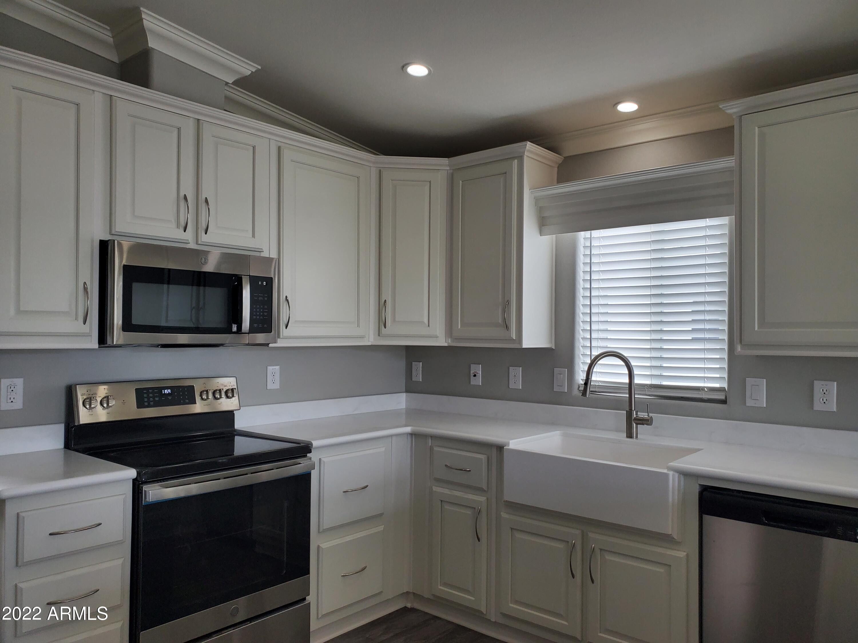 7750 East Broadway Road, Unit LOT 857 Mesa, AZ 85208 - Photo 2 of 17 a kitchen with stainless steel appliances granite countertop a sink a stove a microwave and cabinets