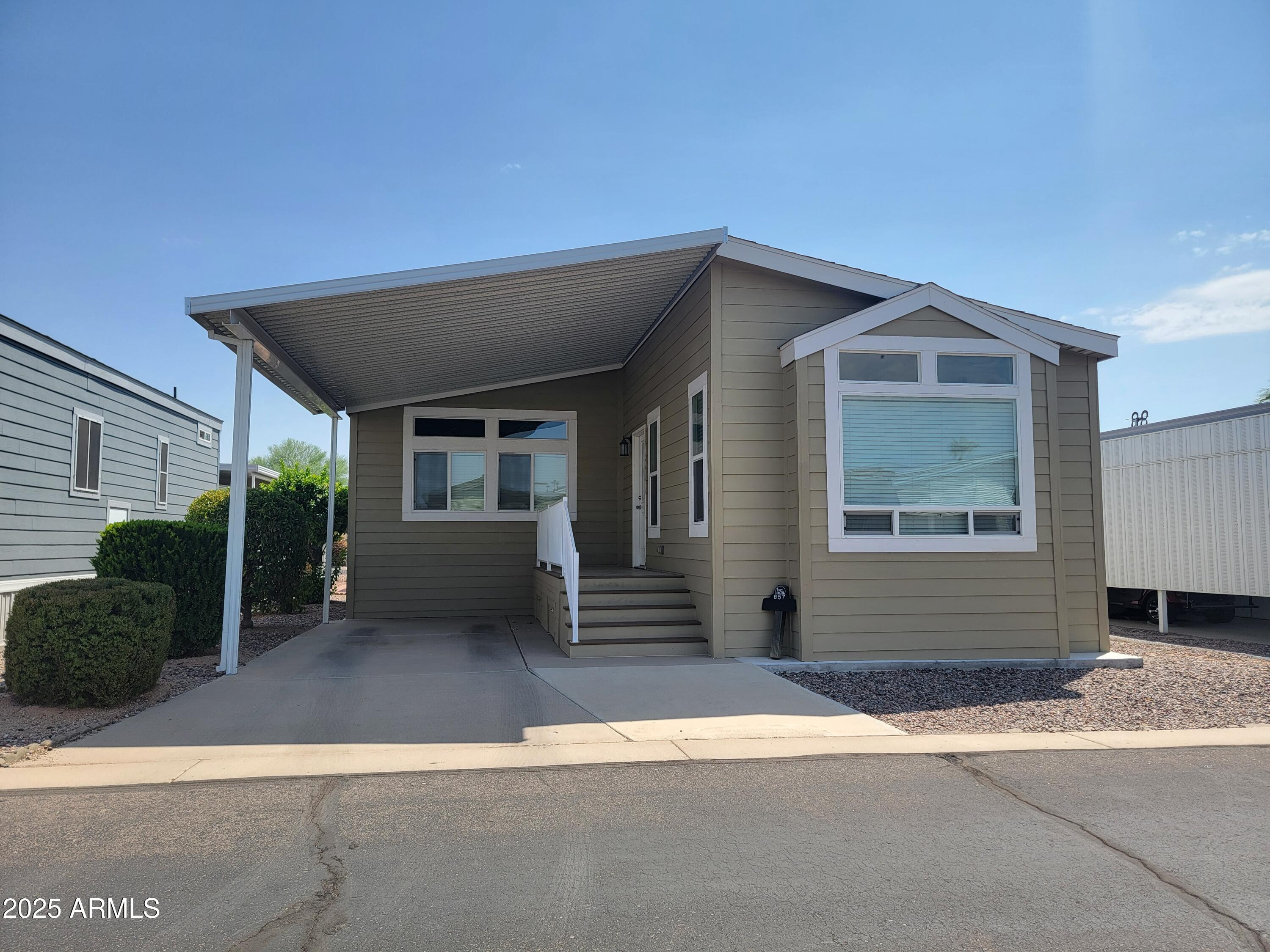 7750 East Broadway Road, Unit LOT 857 Mesa, AZ 85208 - Photo 4 of 17 a front view of a house with a yard and garage