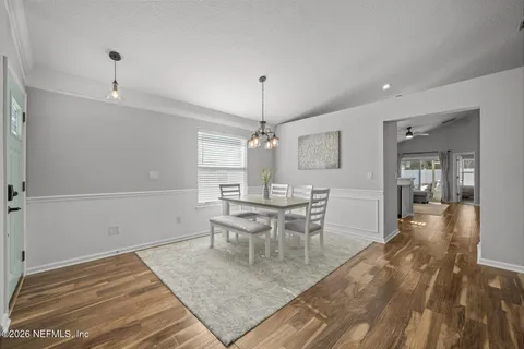 a kitchen with stainless steel appliances kitchen island granite countertop a refrigerator a oven a sink a dining table and chairs with wooden floor