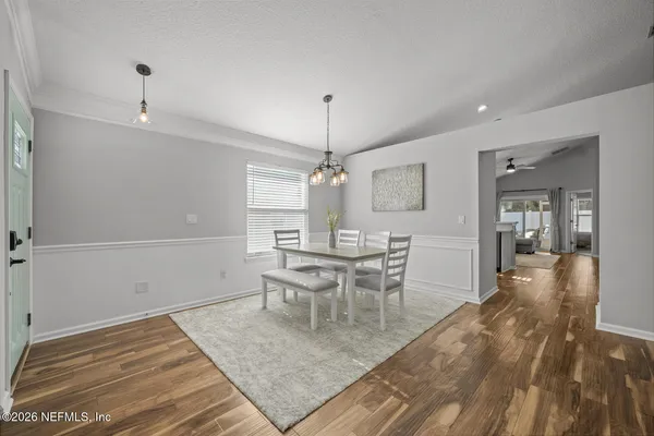 a kitchen with stainless steel appliances kitchen island granite countertop a refrigerator a oven a sink a dining table and chairs with wooden floor