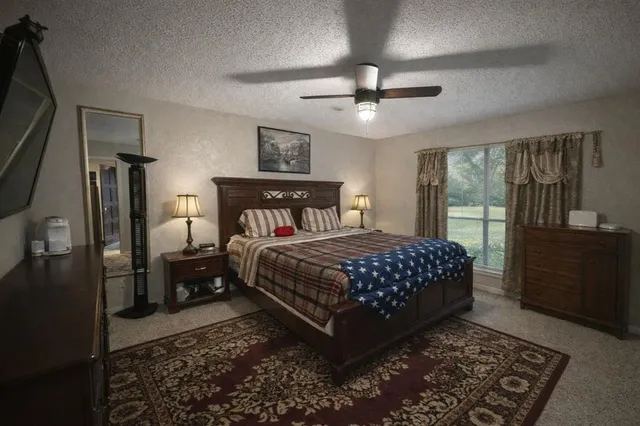 a bedroom with a large bed and a flat tv screen on dresser