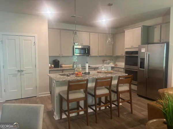 a kitchen with kitchen island granite countertop a table chairs microwave and refrigerator