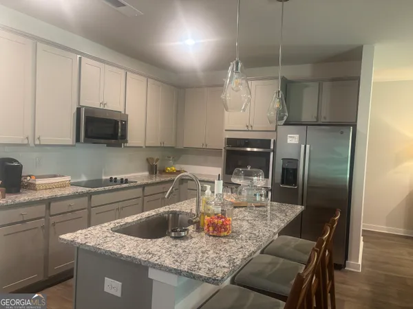 a kitchen with kitchen island granite countertop a sink a counter space appliances and cabinets