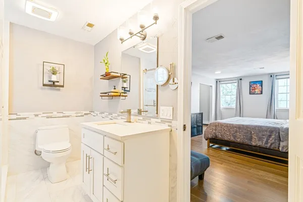 a spacious bathroom with a granite countertop sink a toilet a mirror and shower