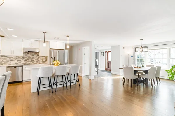 a dining room with wooden floor a chandelier a glass table and chairs