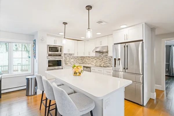 a kitchen with stainless steel appliances a refrigerator a stove a sink a dining table and chairs