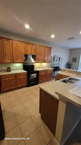 a kitchen with stainless steel appliances a sink a stove a refrigerator cabinets and a window