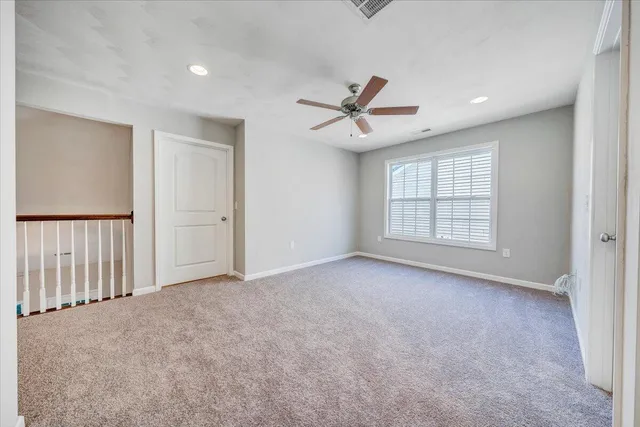 an empty room with windows and ceiling fan