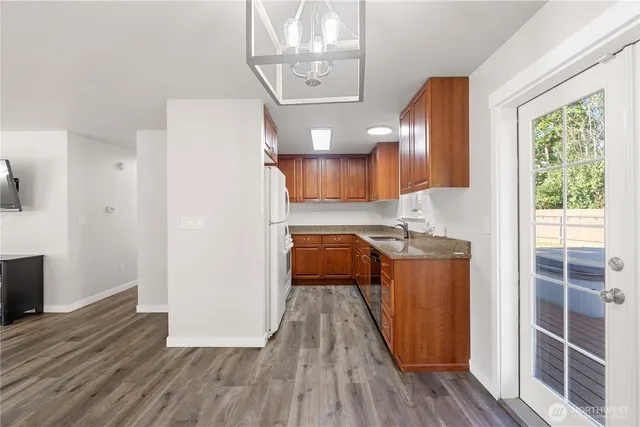 a kitchen with stainless steel appliances granite countertop a refrigerator a sink dishwasher a stove and white countertops with wooden floor