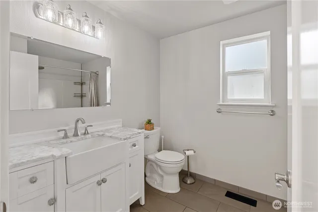 a bathroom with a toilet a sink a mirror and a window