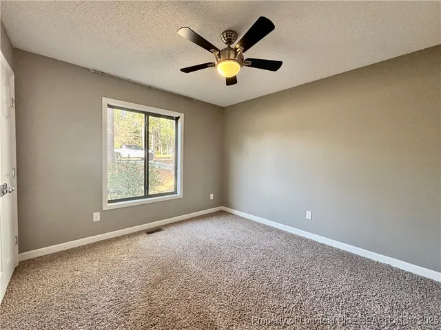 an empty room with ceiling fan and window