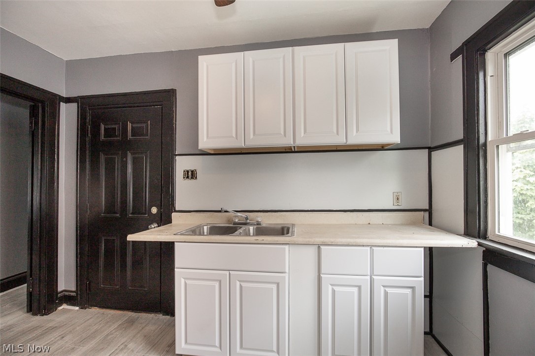 1868-1870 Lampson Road Cleveland, OH 44112 - Photo 9 of 36 Kitchenette area featuring white shaker-style cabinetry, a double basin stainless steel sink, and light-toned countertops