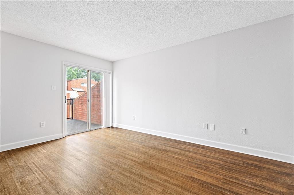 383 Ralph McGill Boulevard Northeast, Unit J Atlanta, GA 30312 - Photo 6 of 28 an empty room with wooden floor and windows