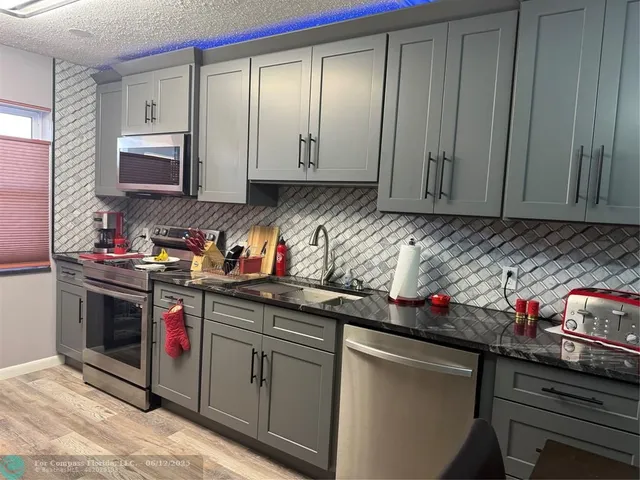 a kitchen with stainless steel appliances granite countertop a sink stove and cabinets