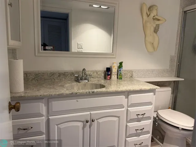 a bathroom with a granite countertop toilet sink and mirror