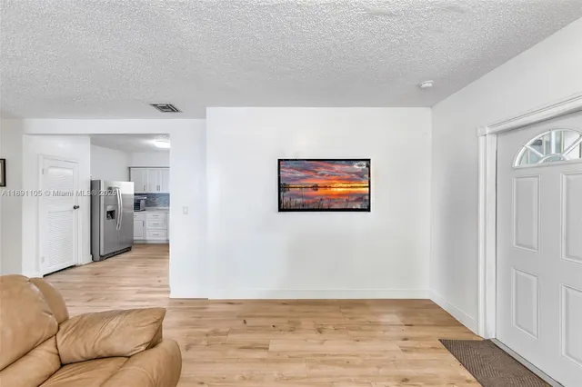 a view of a livingroom with wooden floor and kitchen space