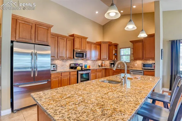 a kitchen with stainless steel appliances kitchen island granite countertop a refrigerator a stove and a sink with granite countertops