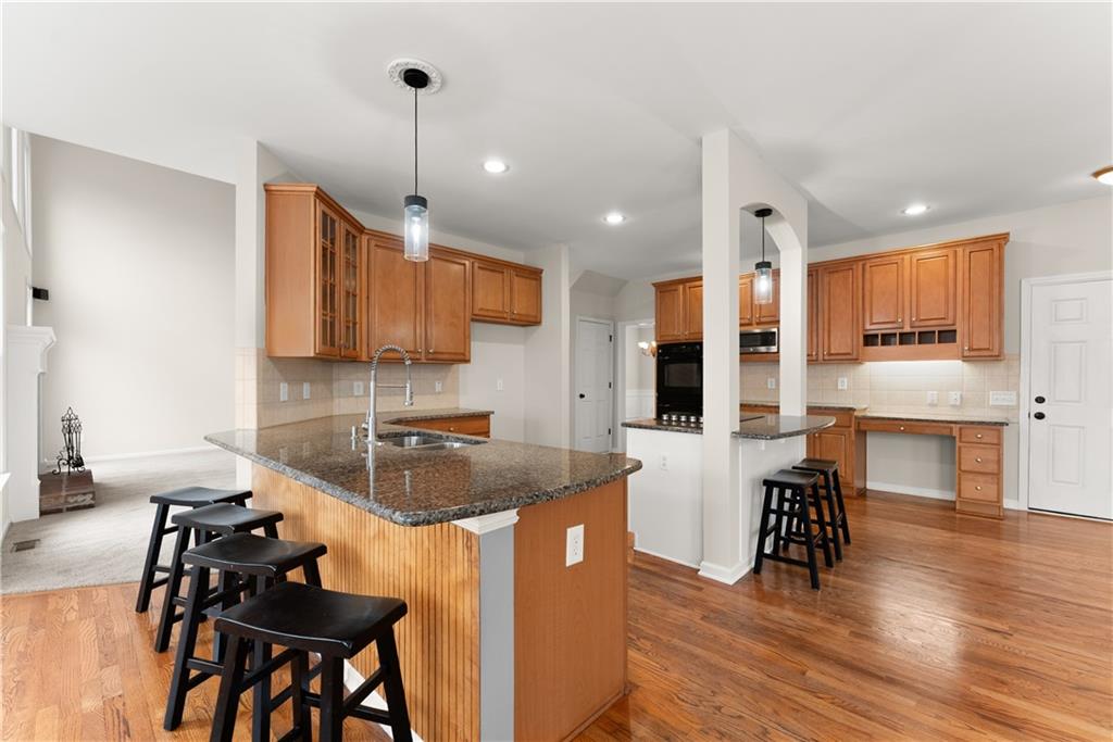 1070 Coleridge Way Suwanee, GA 30024 - Photo 15 of 76 a kitchen with stainless steel appliances granite countertop a stove top oven a refrigerator a sink and a dining table with wooden floor